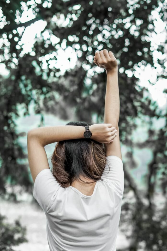 Photo by Timothy Rubby woman in white long sleeve shirt raising her hands