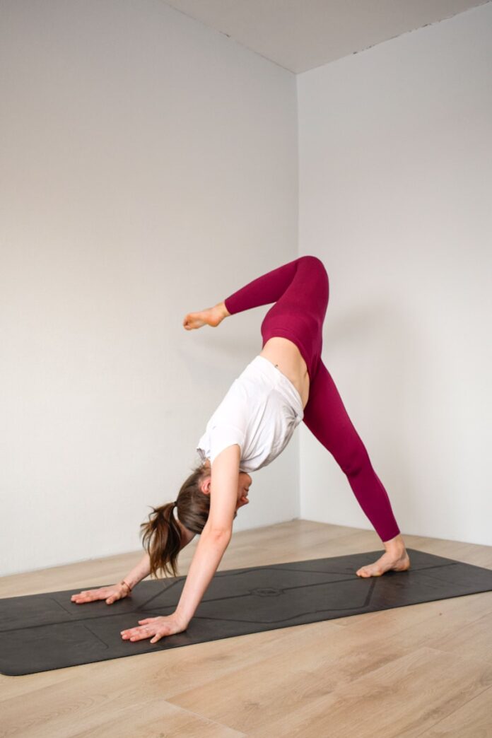 Photo by Nikola Murniece woman in white tank top and purple leggings doing yoga