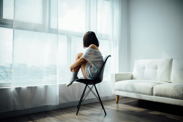 Photo by Anthony Tran woman sitting on black chair in front of glass-panel window with white curtains
