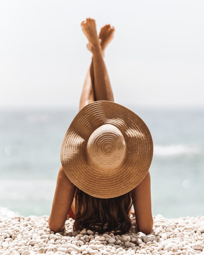 Photo by Jason Mavrommatis woman in brown sun hat standing on beach during daytime