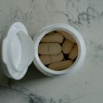 맞춤 영양 보충제, 내 몸에 꼭 맞는 섭취 방법 찾기 Opened bottle of beige pills on marbled surface