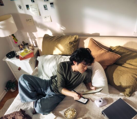 일상 속에 스며드는 AI 건강관리, 나만의 맞춤 루틴 만드는 법 Young man on bed with laptop and snacks