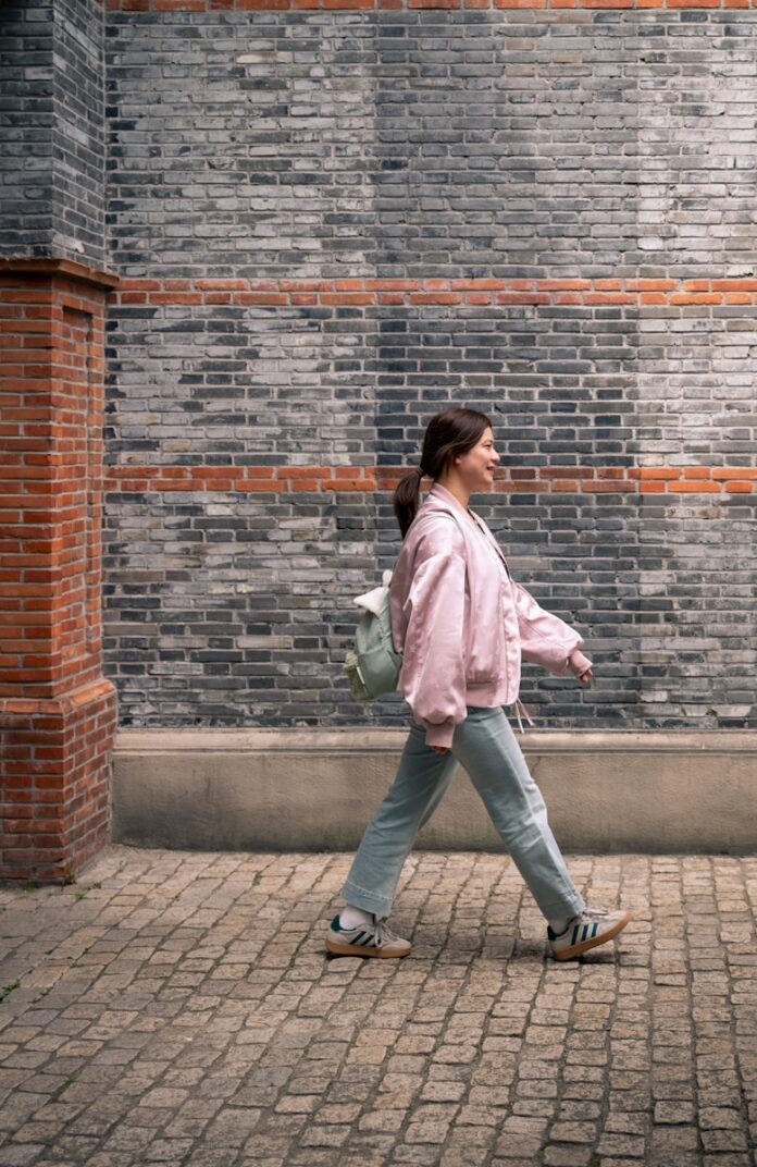 Photo by Declan Sun A woman walks along a brick wall.