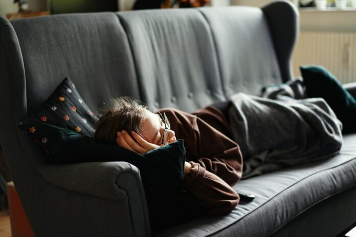 Photo by Adrian Swancar woman in pink jacket lying on gray couch